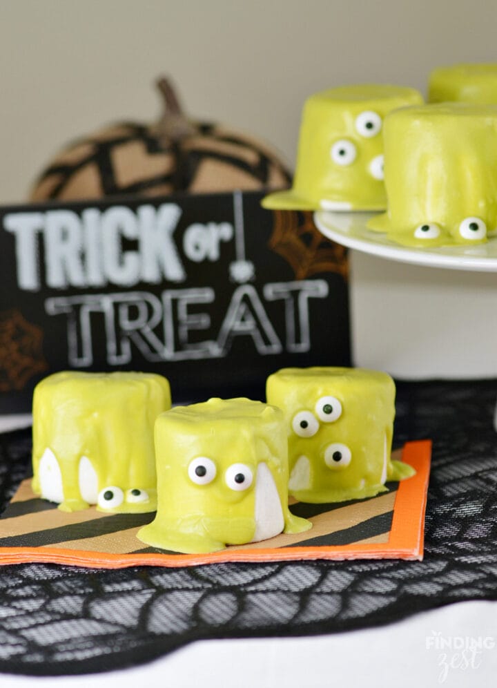 Several large white marshmallows covered in green with candy eyes.