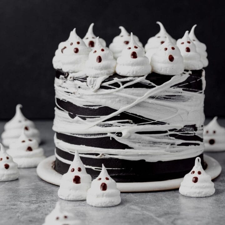 Black cake decorated with white merengue ghosts.