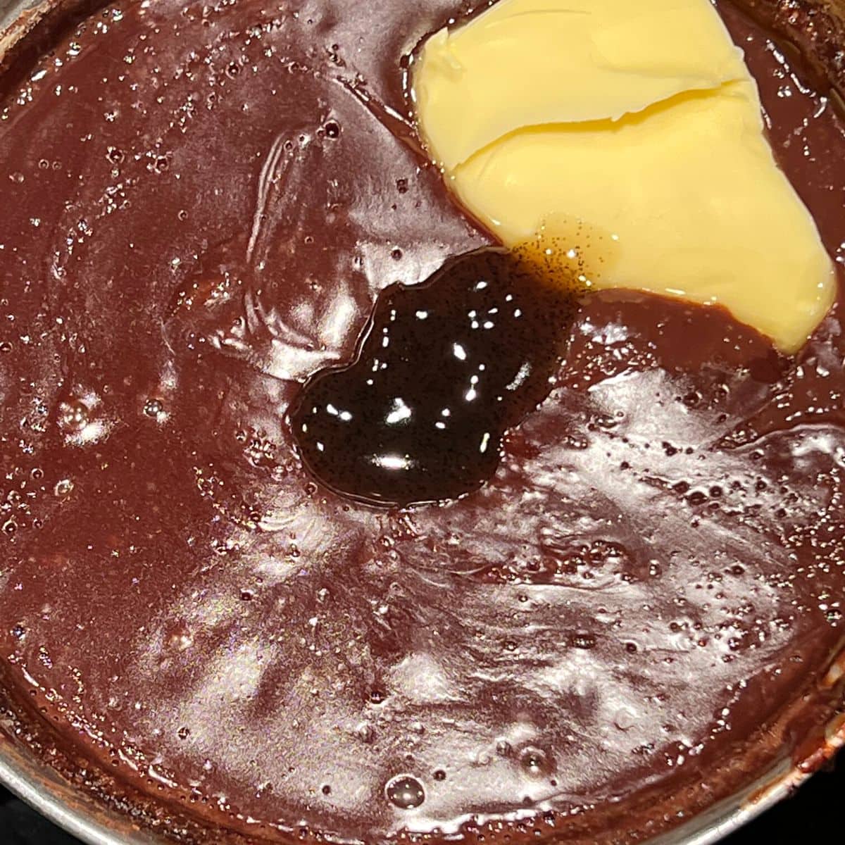 Adding vanilla and butter to chocolate mixture in saucepan.
