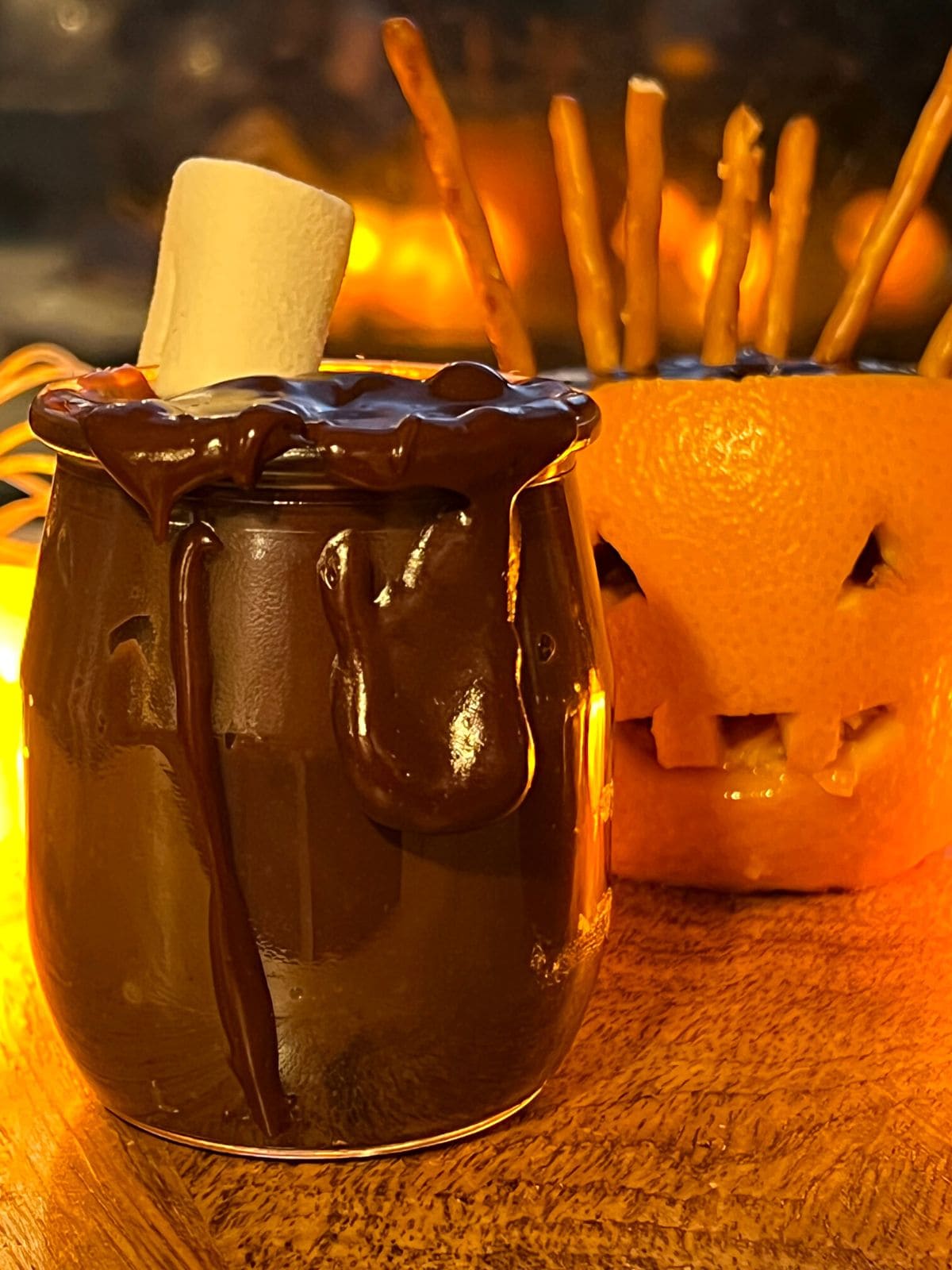 Chocolate pudding with white marshmallow next to orange jack-o-lantern.