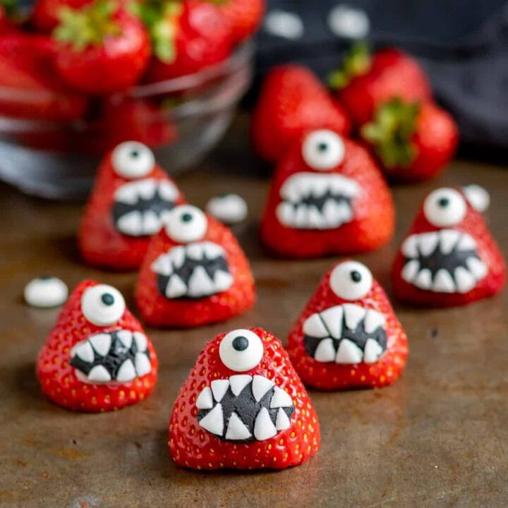 Strawberries decorated with candy eyes and toothy open mouths.