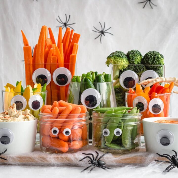 Assorted vegetables and dips in glass jars with eyes affixed.