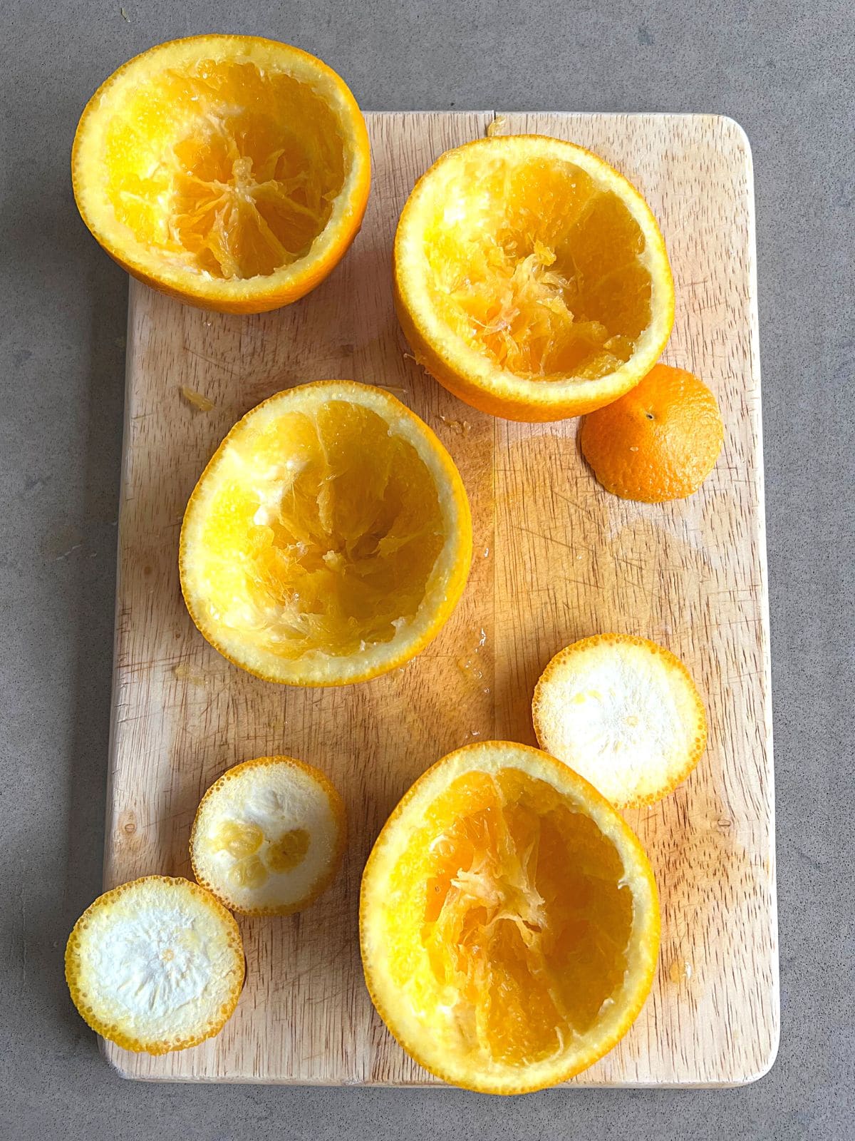 Hollowed out large oranges on wooden cutting board.