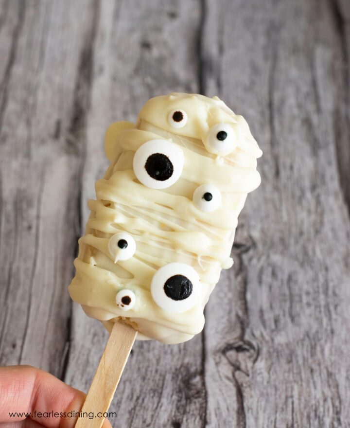 White cakesicle decorated like a mummy with candy eyes.