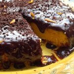 Chocolate covered orange cake with slice cut out.