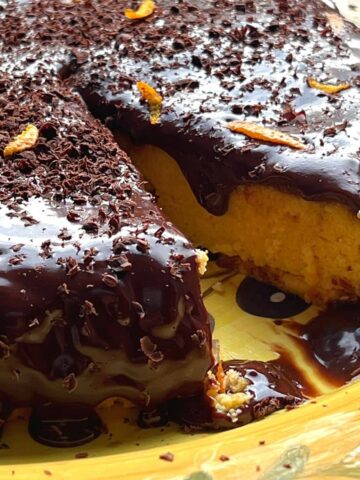 Chocolate covered orange cake with slice cut out.