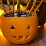 Orange jack o lantern filled with chocolate pudding and stick pretzels.