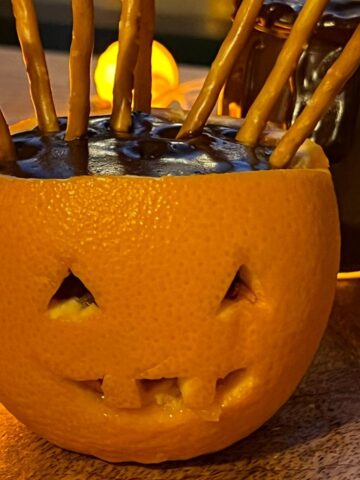 Orange jack o lantern filled with chocolate pudding and stick pretzels.