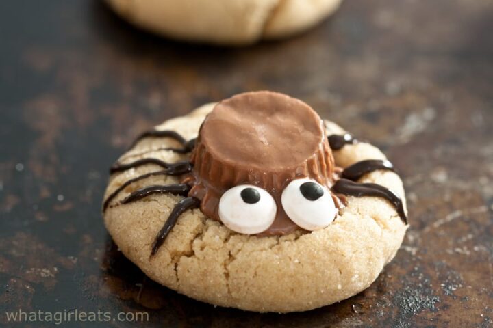 Cookie with spider decoration and candy eyes on kitchen counter.