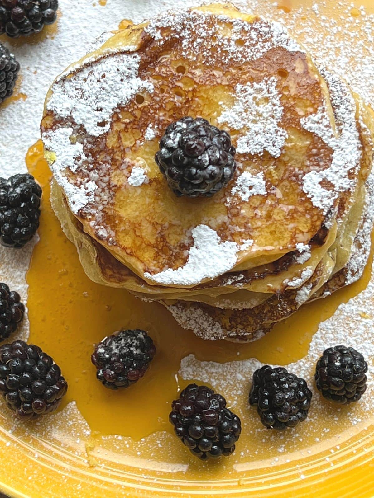 Stacked pancakes with syrup and blackberries.