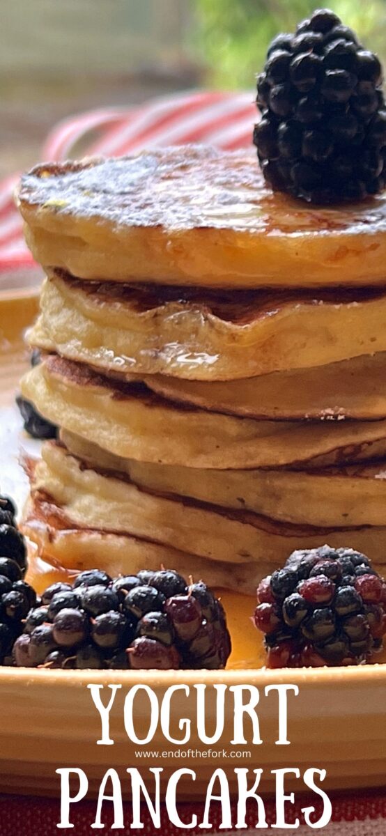 Pin image of pancakes from side with blackberries on yellow plate.