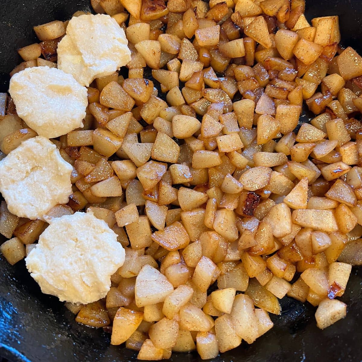 Arranging biscuit dough on pears in skillet.