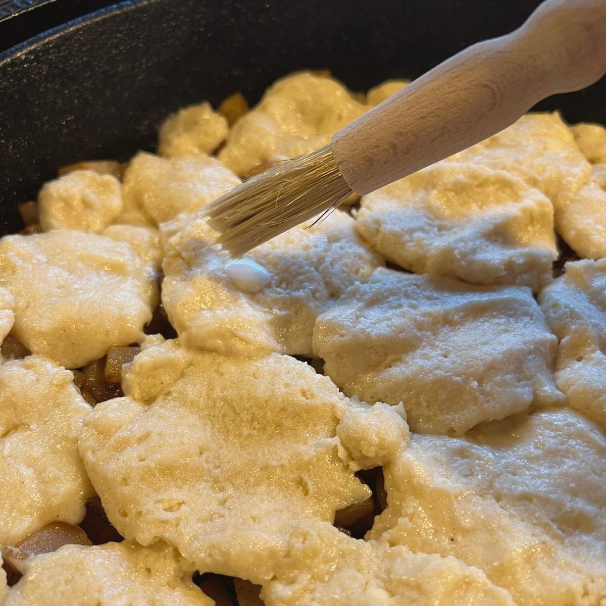 Applying glaze to biscuit dough.