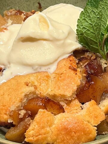 Close up of pear cobbler with scoop of vanilla ice cream.