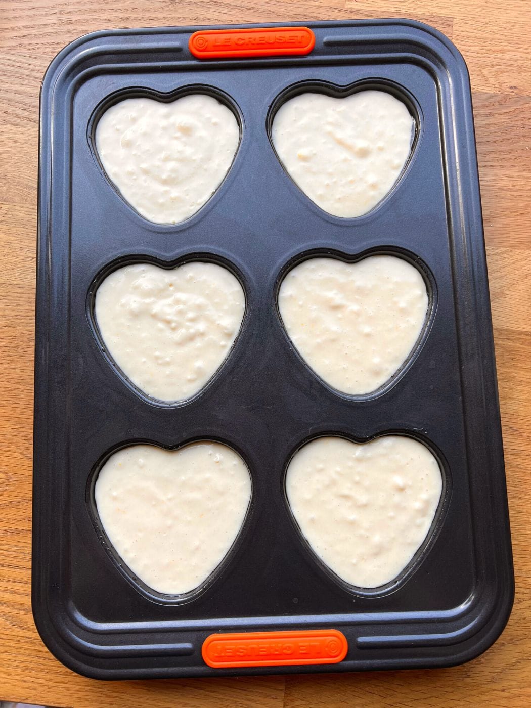 Cake batter in heart muffin baking tray.