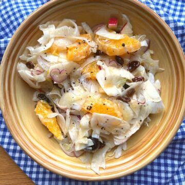 Fennel salad in yellow bowl on chequered cloth.