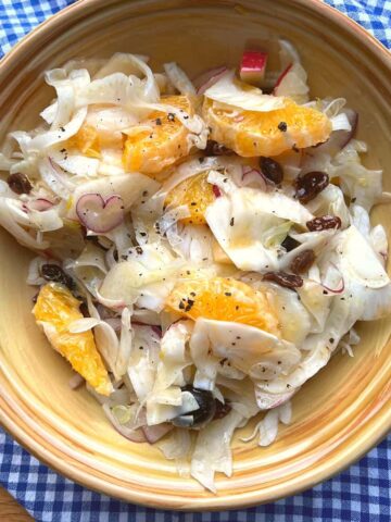 Fennel salad in yellow bowl on chequered cloth.