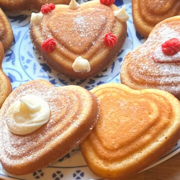 Mini heart shaped decorated cakes on a plate.