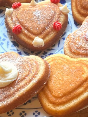 Mini heart shaped decorated cakes on a plate.