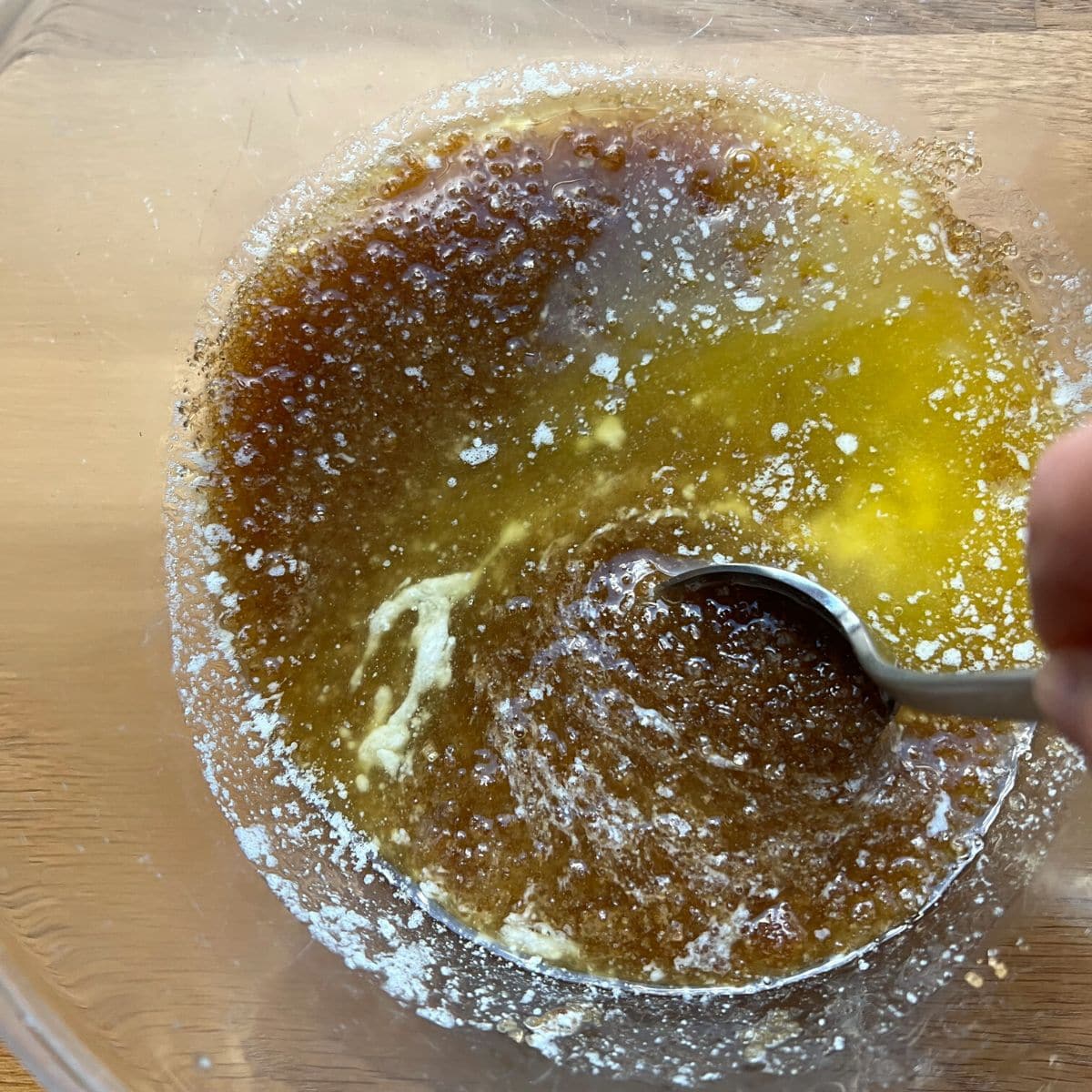 Mixing melted butter and sugar in glass bowl.