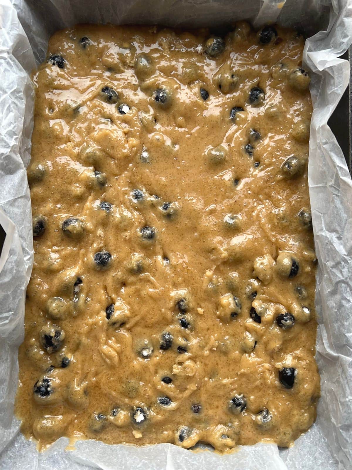 Blueberry batter in a lined baking pan.