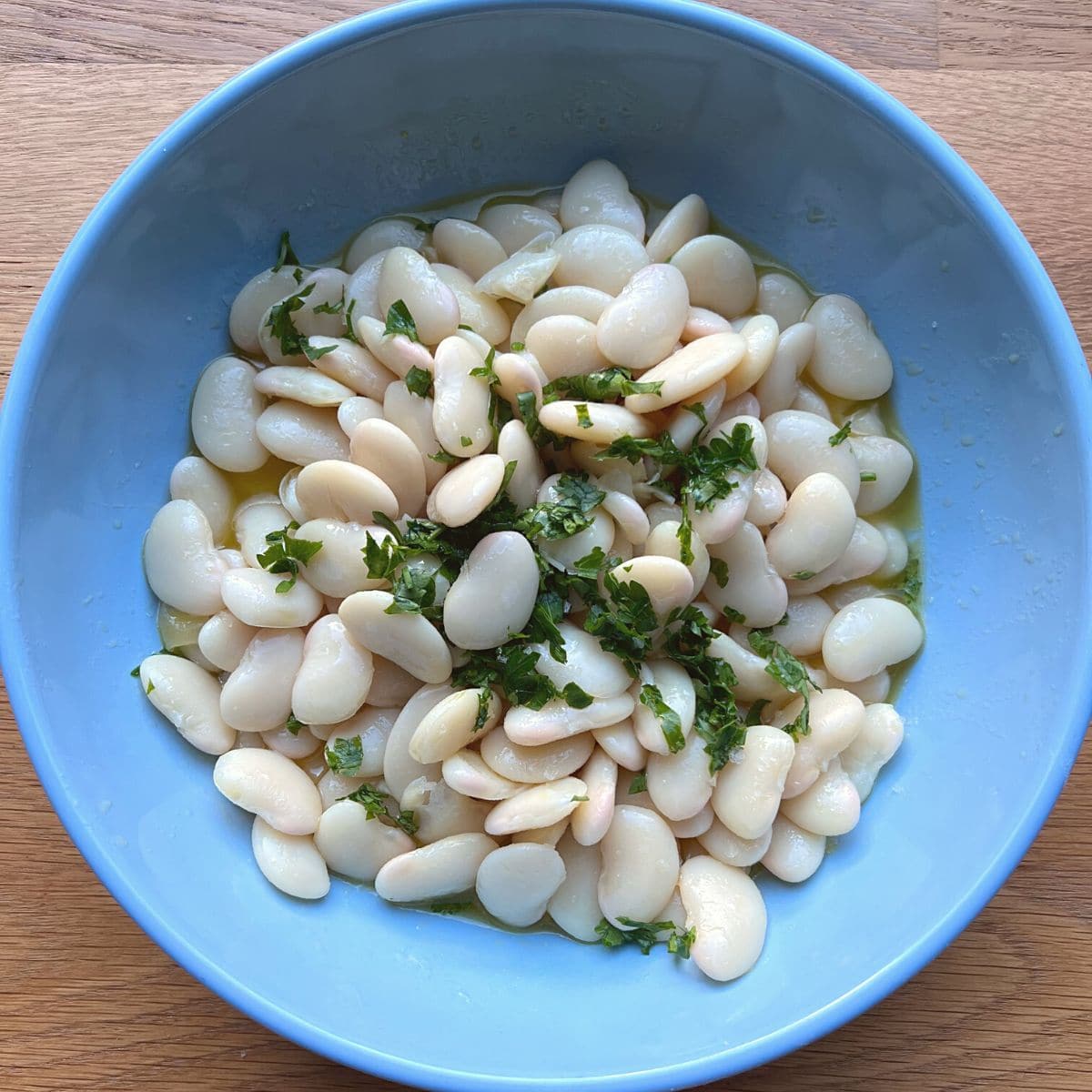 Butter beans and parsley in blue bowl.