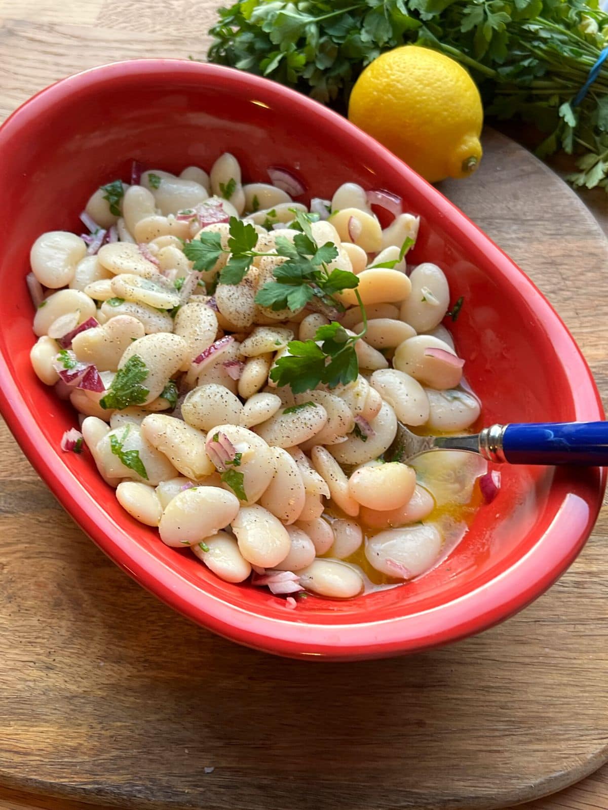 Butter beans salad in red bowl.