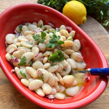 Butter beans salad in red bowl.