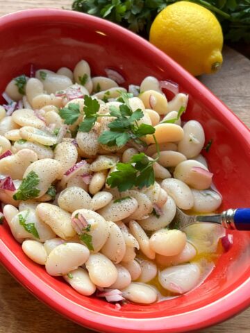 Butter beans salad in red bowl.