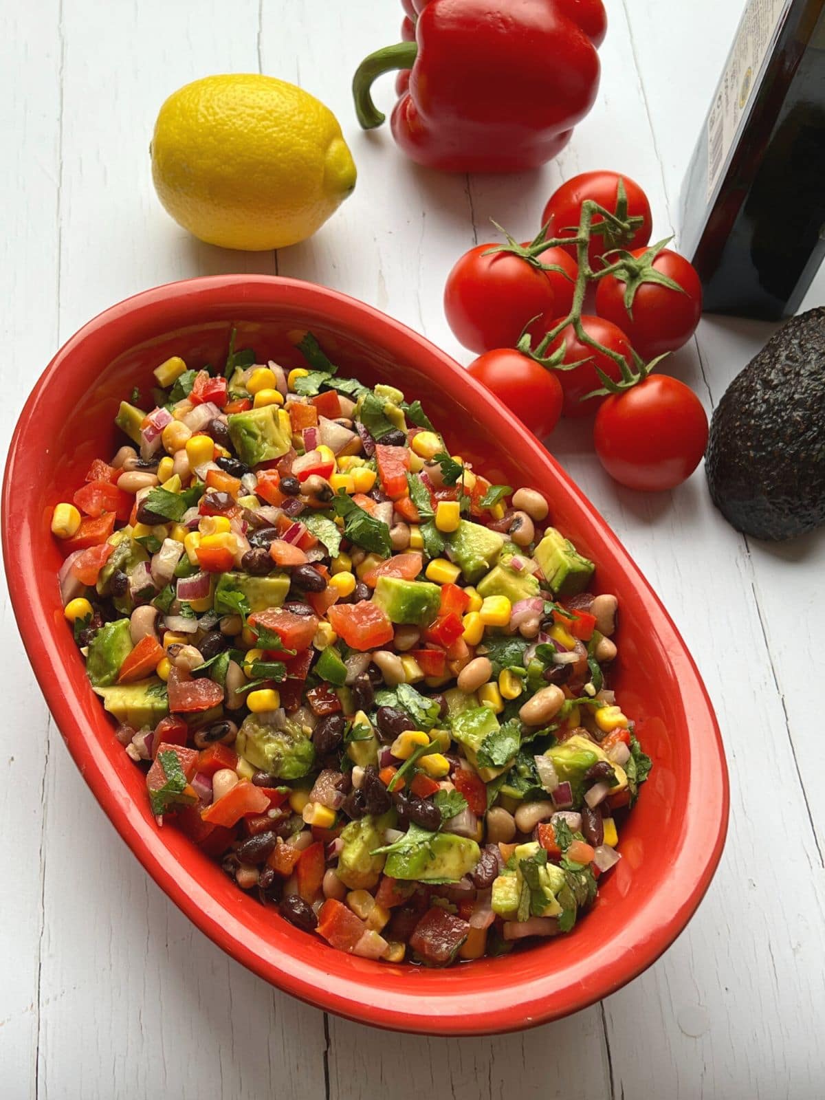 Cowboy salsa in red bowl on white table.