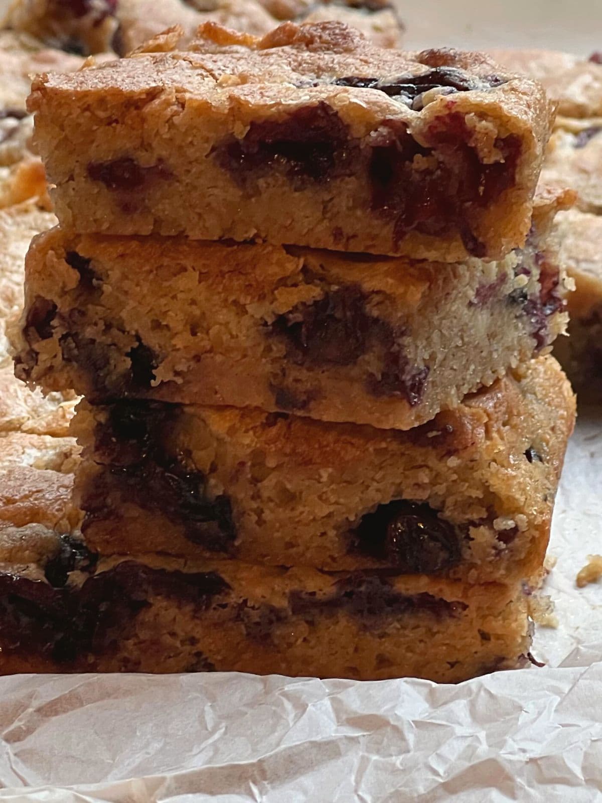 Stack of four blueberry blondies on baking paper.