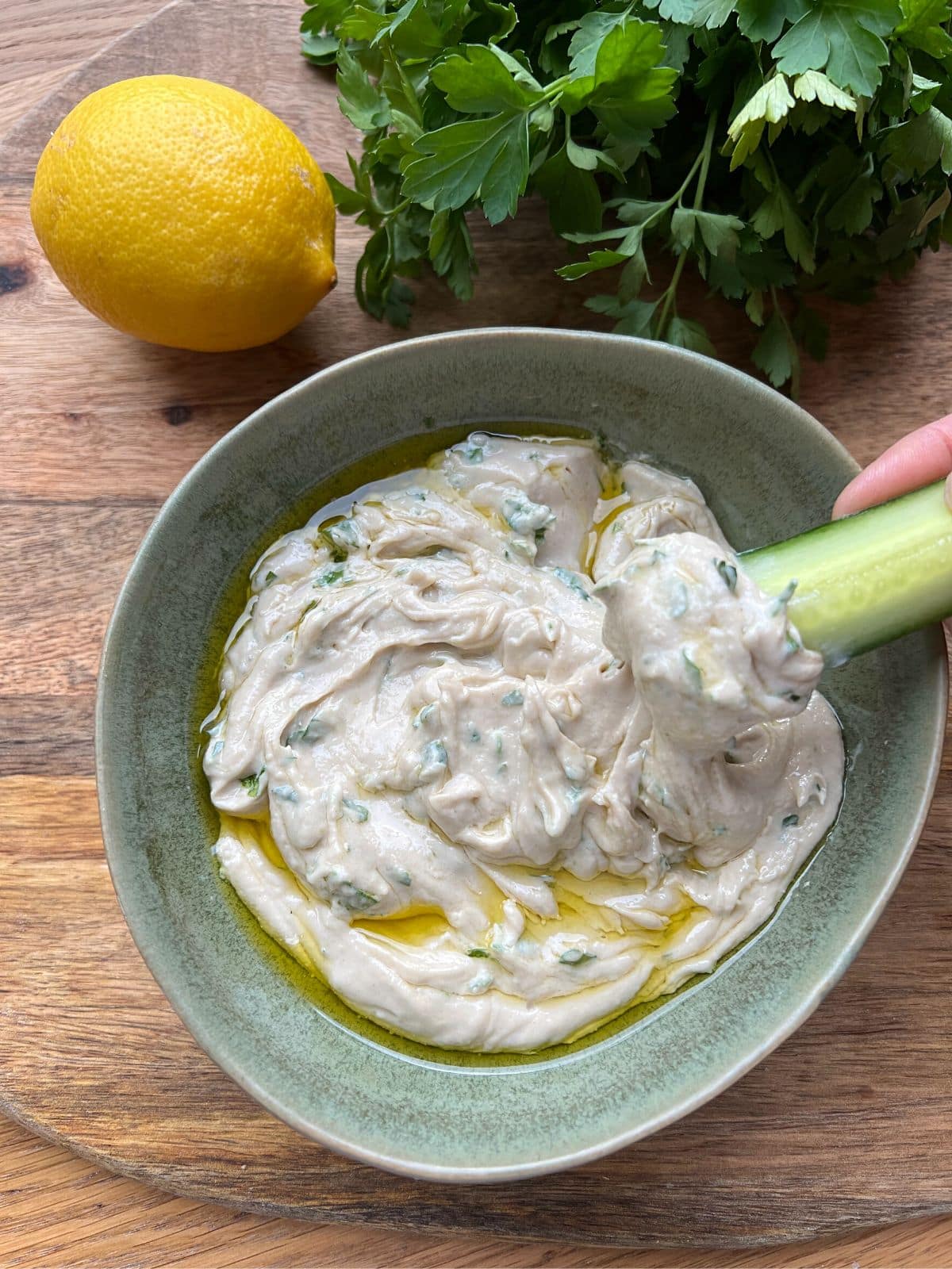 Dipping cucumber stick into tahini sauce as a dip.