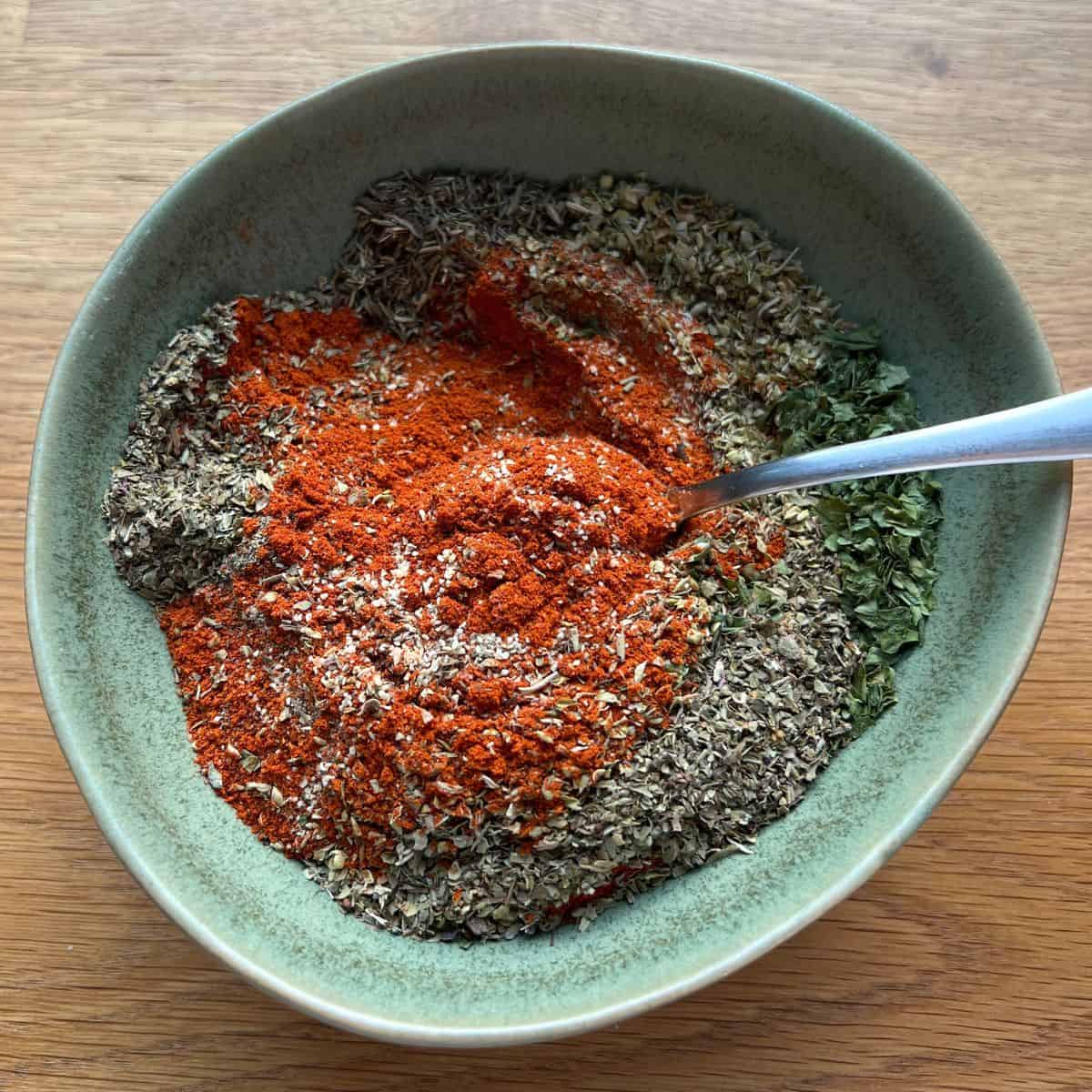 Mixing creole spices in a green bowl.