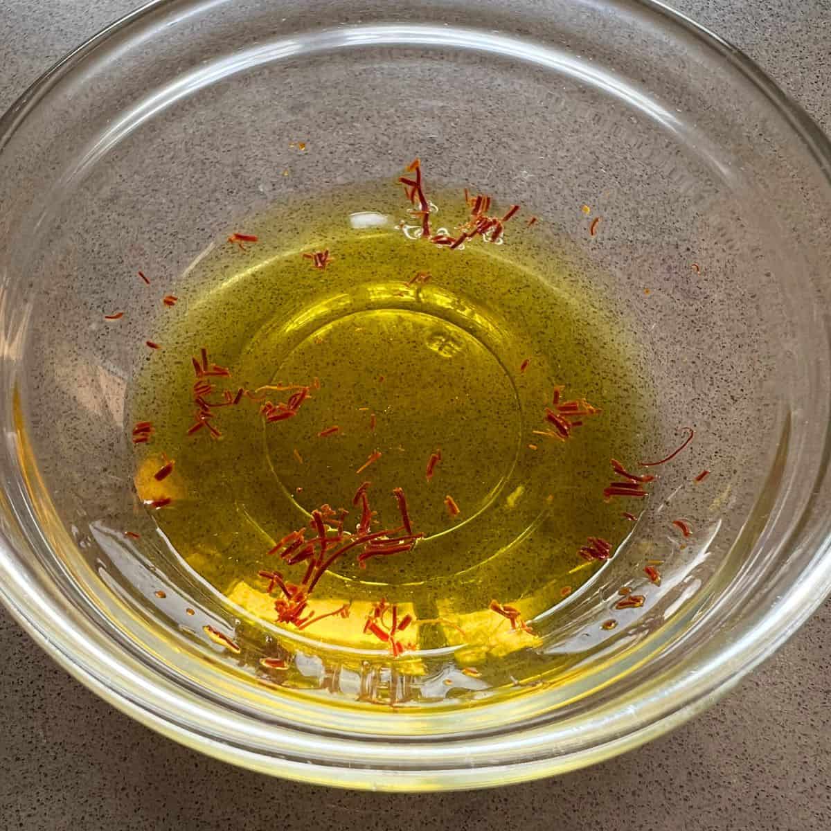 Small glass bowl with crushed strands of saffron in water.