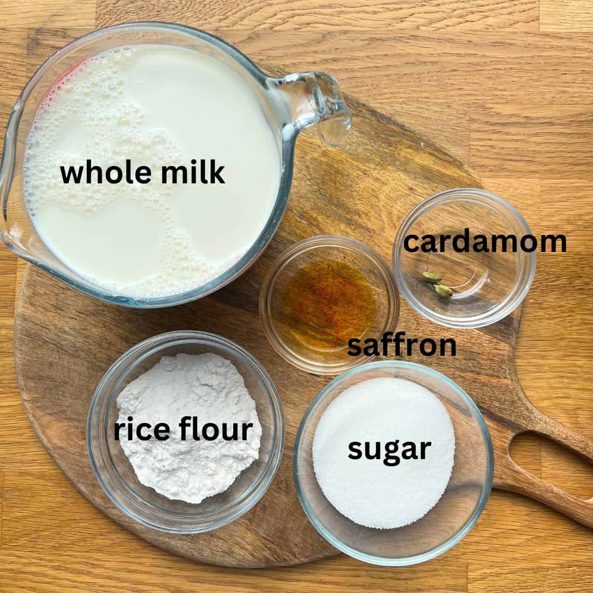 Small bowls on wooden surface containing ingredients for making firni.