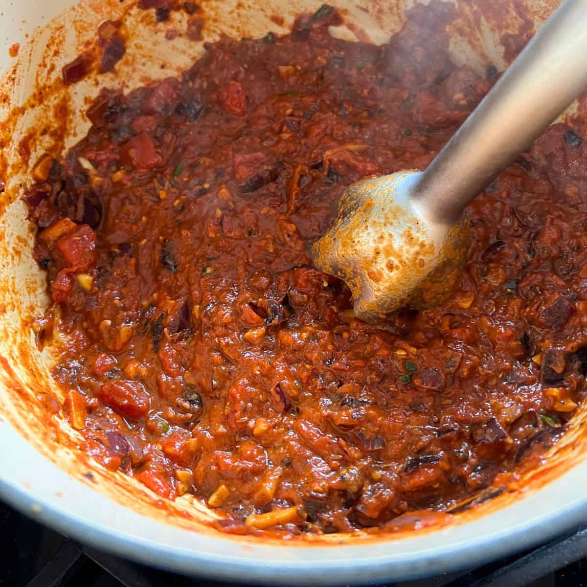 Blending the sauce mixture with a stick blender.