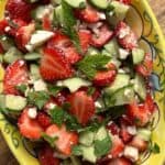 Strawberry salad in yellow painted bowl.