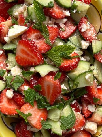 Strawberry salad in yellow painted bowl.