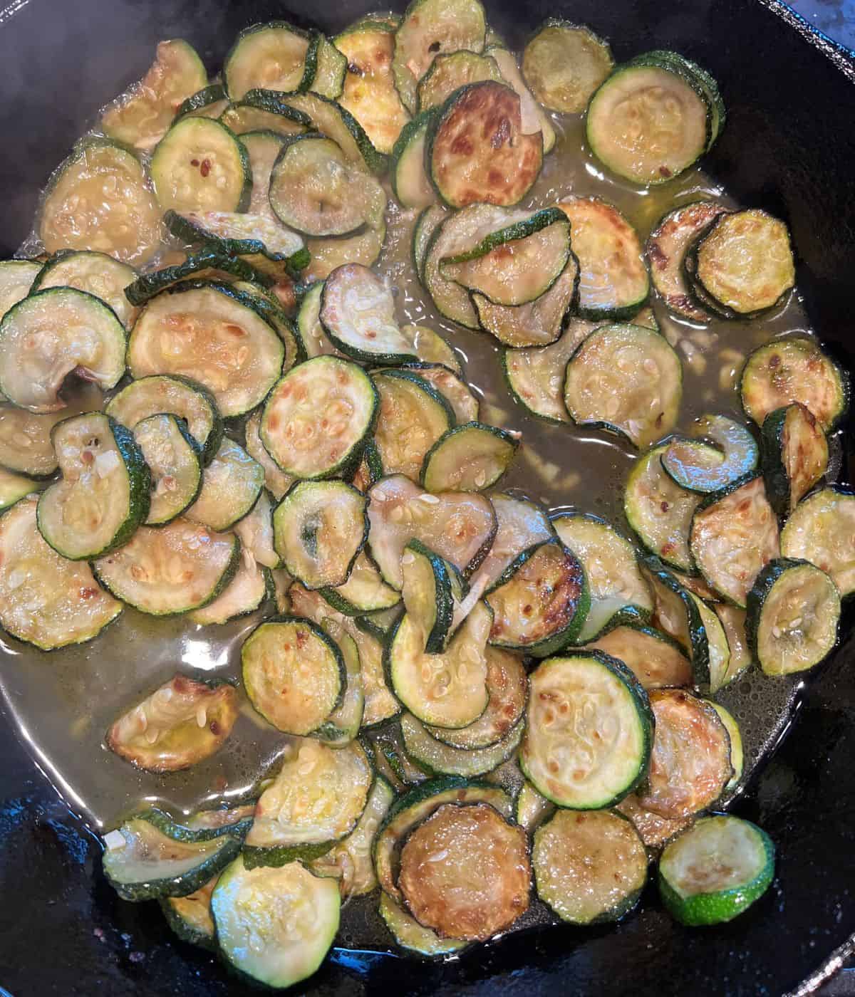 Boiling fried zucchini in cast iron skillet.