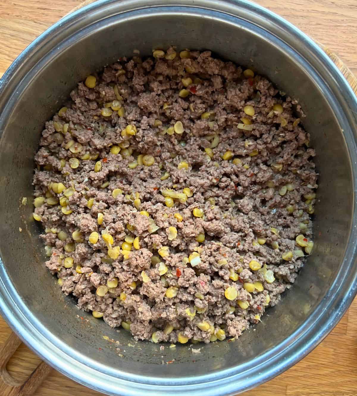 Cooked meat and lentils with spices in large saucepan.