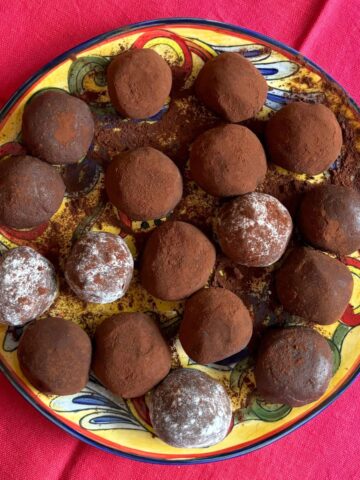 Plate of chocolate fudge balls dusted in cocoa powder on red napkin.