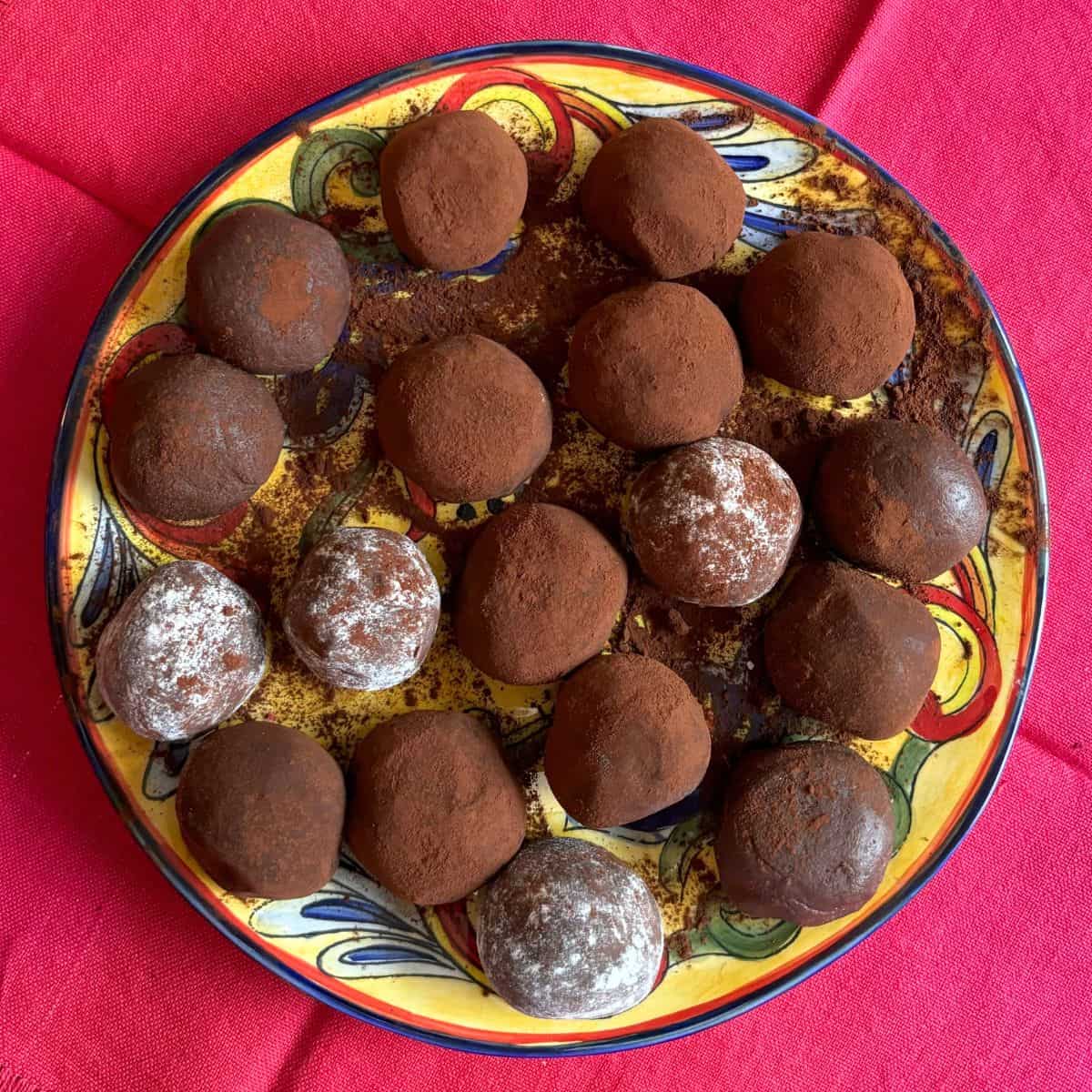 Plate of chocolate fudge balls dusted in cocoa powder on red napkin.