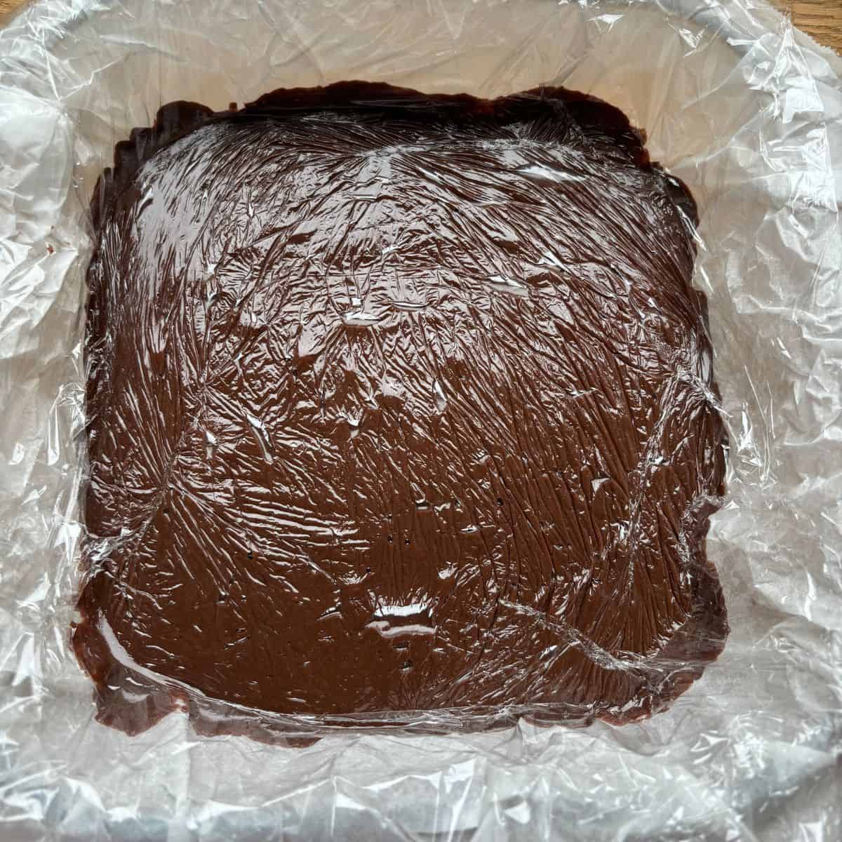 Fudge in lined dish covered with plastic wrap.
