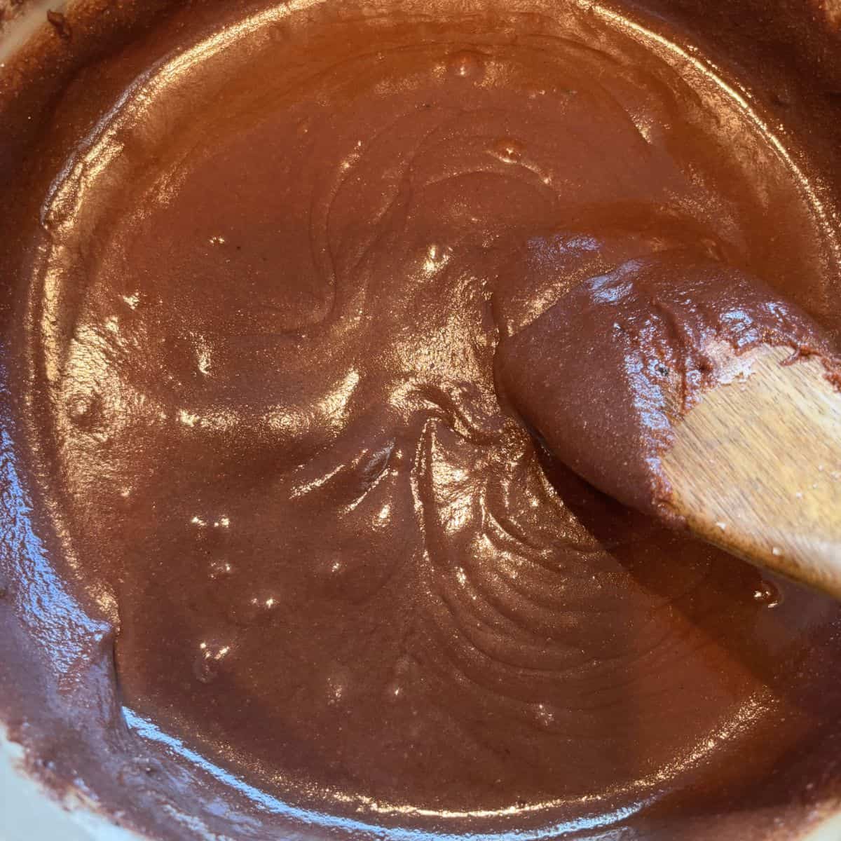 Stirring fudge mixture in pan with wooden spoon.