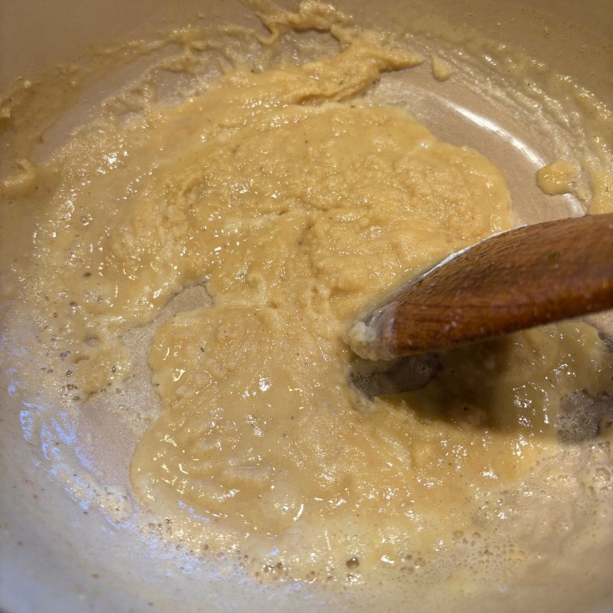 Stirring roux in saucepan with wooden spoon.