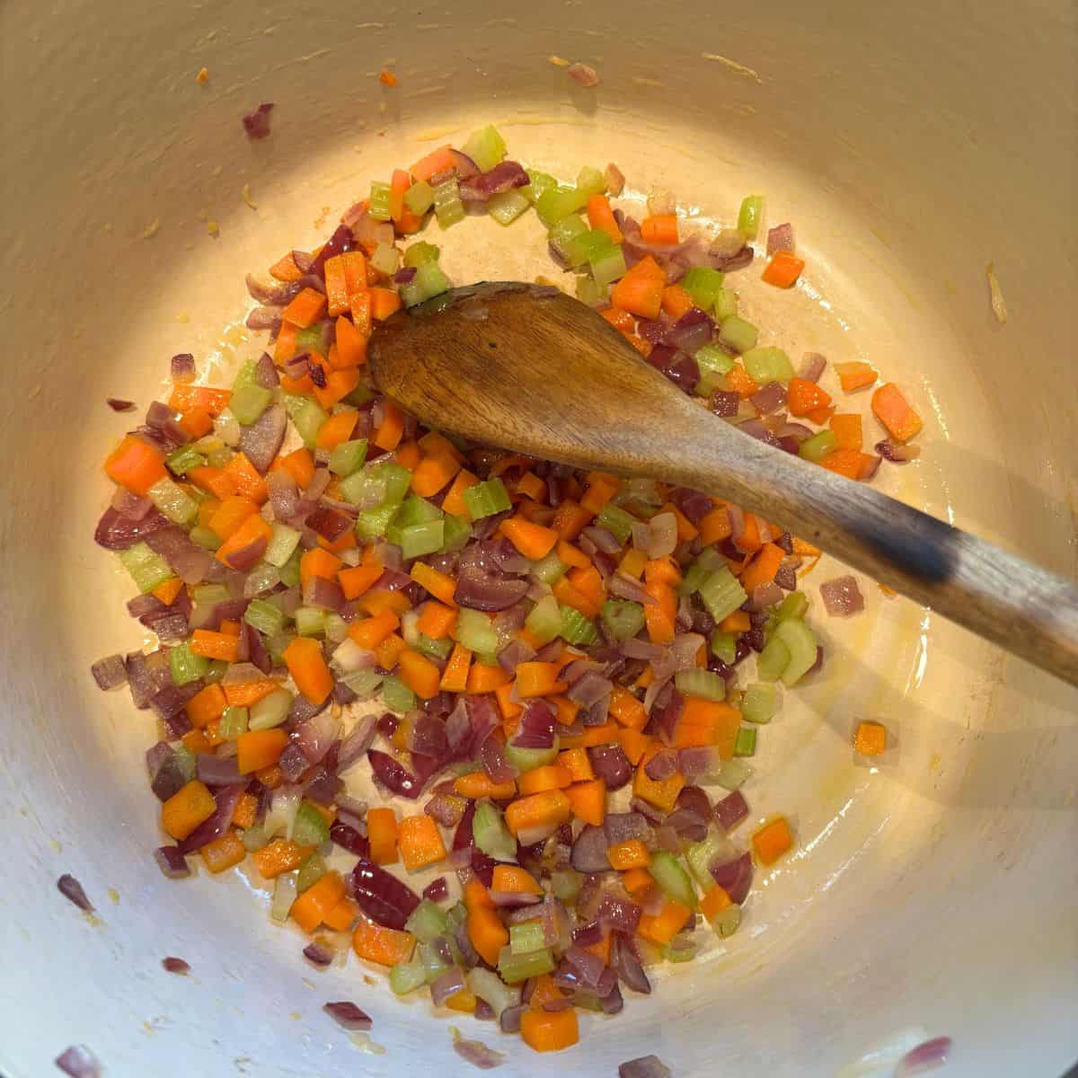Softened soffritto in pan with wooden spoon.