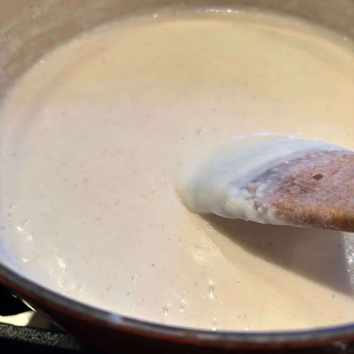 Stirring bechamel as it thickens in pan with wooden spoon.
