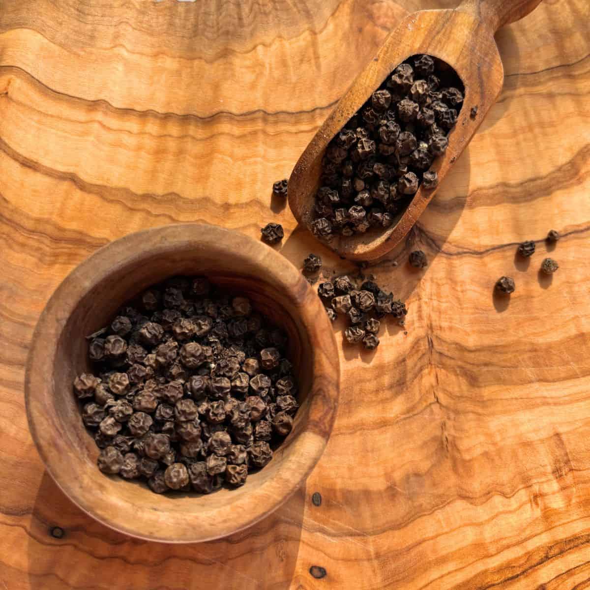 Dried black peppercorns in wooden bowl